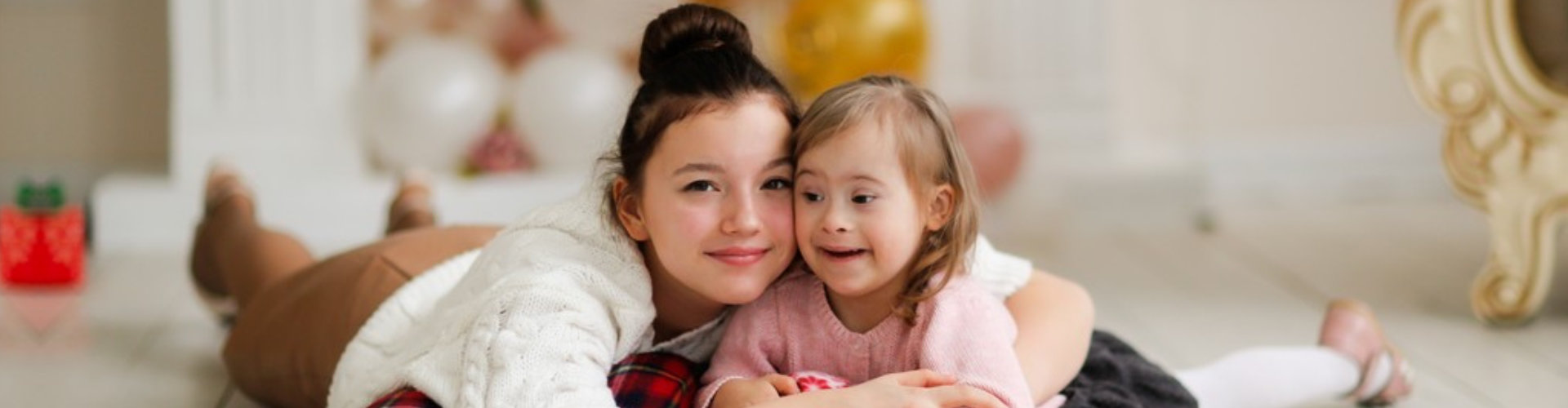 young girl hugging her smiling younger sister